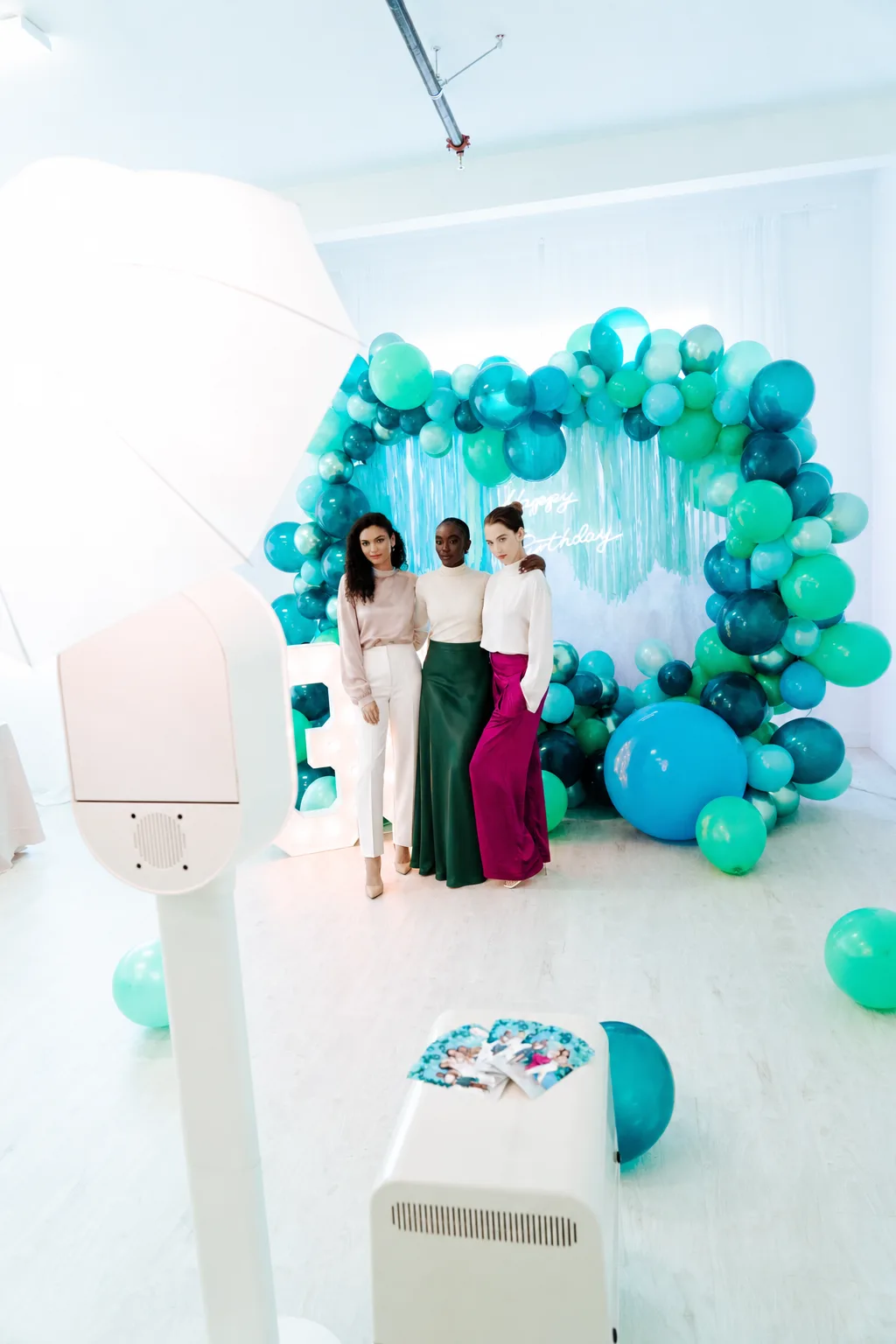 Friends posing in front of a balloon arch at a birthday party